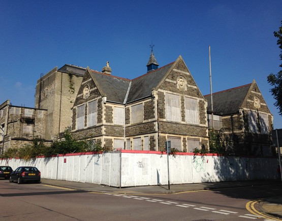 The exterior of Swindon Mechanics Institute with white hoarding around the perimeter. 