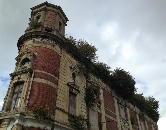 Looking up towards to roof of Swansea Palace  Theatre - loys of foliage and shrubbery growing from various points across the facade. 