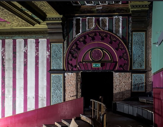 Magenta, teal and white arabesque detailing around the exit door at the back left of the auditorium of Walthamstow Granada