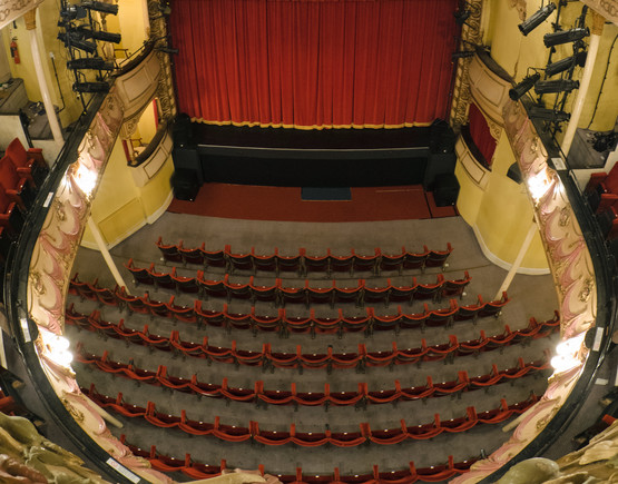 Theatre Royal Margate interior showing the red seats in the stalls, and the two horseshoe balconies decorated with swags in cream, gold and dusty pink.