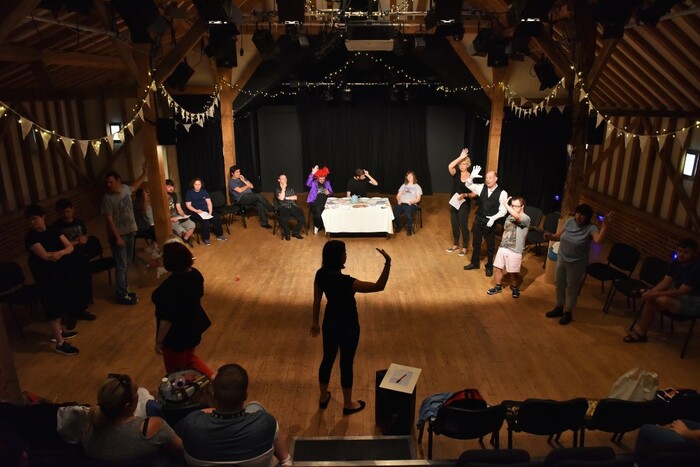 Show at Hanger Farm Theatre with people standing and sitting in wooden floored performance space