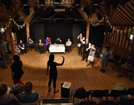 Show at Hanger Farm Theatre with people standing and sitting in wooden floored performance space