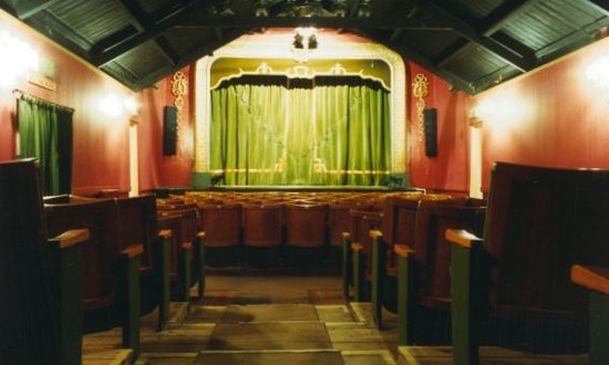 The auditorium of the Robin Hood Theatre. A view from the back of the flat floor stalls towards the stage. 