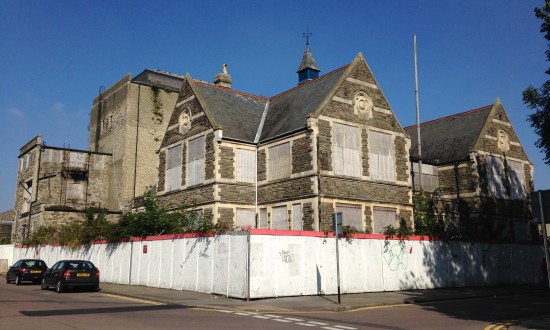The exterior of Swindon Mechanics Institute with white hoarding around the perimeter. 
