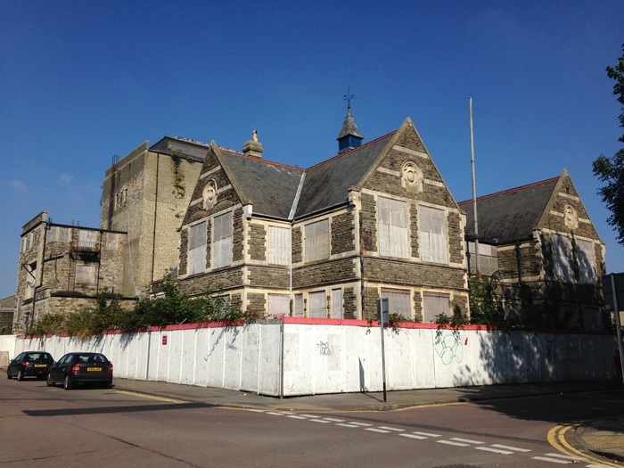 The exterior of Swindon Mechanics Institute with white hoarding around the perimeter. 