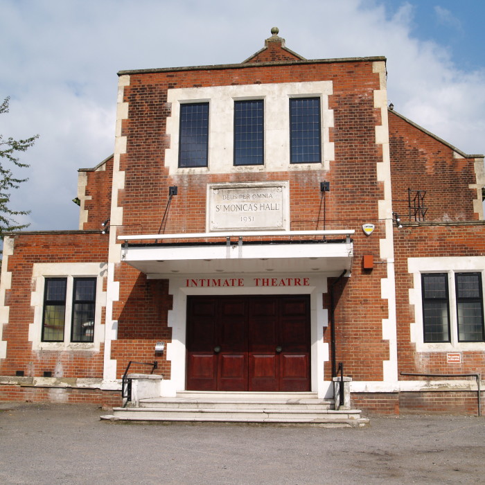 The exterior of Intimate Theatre, with a car parking area in the foreground.