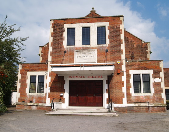 The exterior of Intimate Theatre, with a car parking area in the foreground.