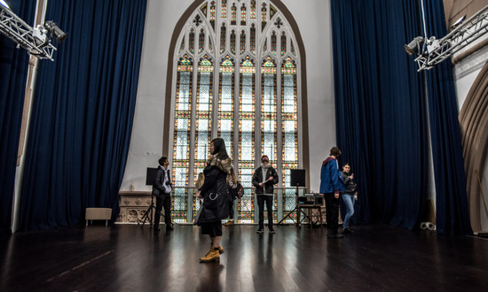 Audiences milling in front of the stained glass window in the main hall of Trinity Theatre.