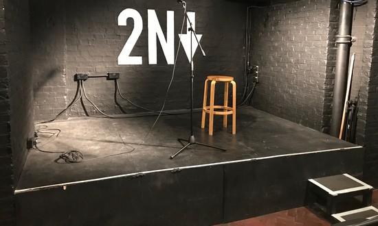 The stage in the black box auditorium of 2Northdown, with steps up to stage left, and 2Northdown;s logo projected on the backwall.