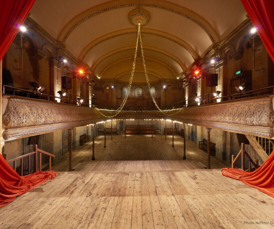 Auditorium of Wilton's Music Hall with wooden floors and red curtain