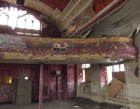 Dilapidated section of the balcony at the back of the theatre space at the Mechanics auditorium in 2003, with peeling red paint and some boarded up windows