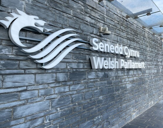 Wall of the Welsh Parliament building with logo and words Senedd Cymru Welsh Parliament.
