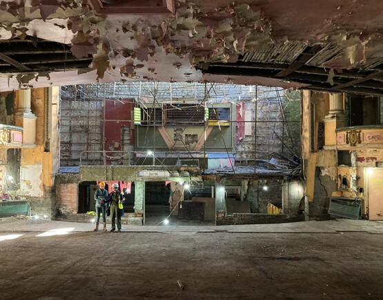 People in protective clothing inspecting the auditorium of a derelict historic theatre