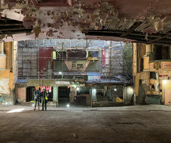 People in protective clothing inspecting the auditorium of a derelict historic theatre