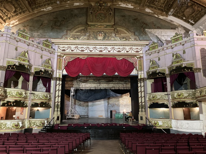 Auditorium of historic Morecambe Winter Gardens with lavishly decorated ceiling and man playing the organ.
