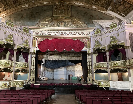 Auditorium of historic Morecambe Winter Gardens with lavishly decorated ceiling and man playing the organ.