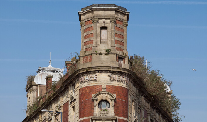 Large triangular shaped building on the corner of a road 