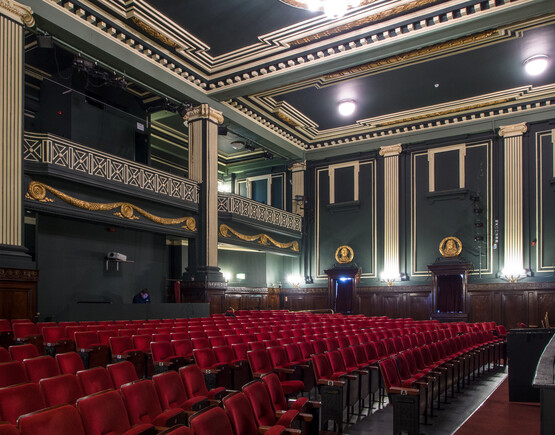 Auditorium of Epstein Theatre, viewed from the side of the stalls, showing rows of red seats, in contrast with the dark green, cream and gold walls