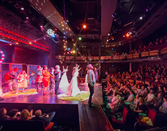 Performers on stage in front of a packed audience at Chester's Storyhouse.