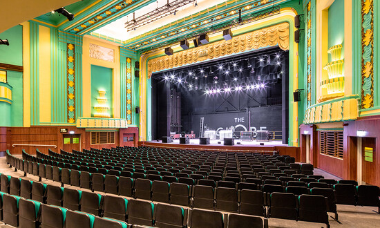 Interior of theatre auditorium in the Art Deco style with green and yellow detailing. 